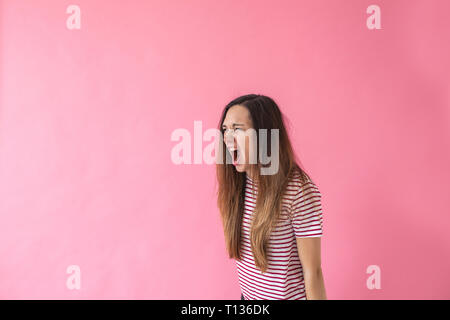 Porträt eines Mädchens auf einem rosa Hintergrund Die ruft oder Emotionen zum Ausdruck bringt. Stockfoto
