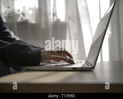 Weibliche Hände Schreiben auf der Tastatur des Laptops auf den Hintergrund des Fensters Stockfoto