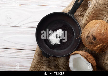 Kokosnuss, Shell mit Fleisch, Gusseisen Skillet auf Hanf Sack auf weißen Küche aus Holz Tisch Stockfoto