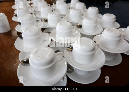 Teetassen und Untertassen stapeln sich in einem Café in Chichester, West Sussex, Großbritannien. Stockfoto