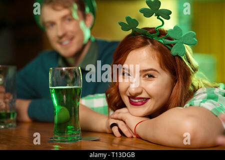 Rothaarige hübsches Mädchen mit Shamrock headwear an der Theke sitzen Stockfoto