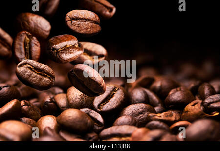 Kaffeebohnen fallen auf Stapel, schwarzer Hintergrund mit Kopie Raum, in der Nähe Stockfoto