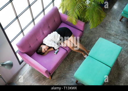 Blick von oben auf die müde Geschäftsfrau schlafen auf Violett couch in Office Stockfoto