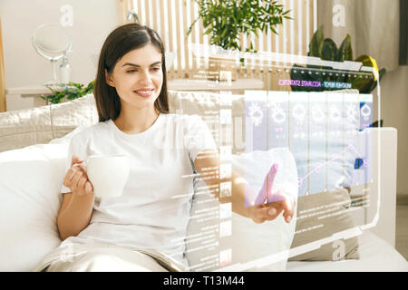 Smiling brunette Mädchen mit futuristischen Hologramm Touchscreen für das Durchsuchen Wetter Stockfoto