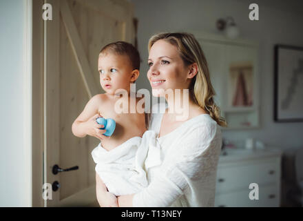 Lächelnde Mutter holding Toddlersohn im Bad zu Hause Stockfoto