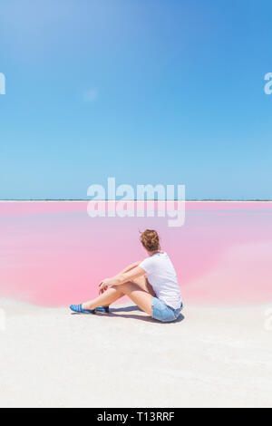 Mexiko, Yucatan, Las Coloradas, Pink Lake salt lake, Frau sitzt am Strand Stockfoto