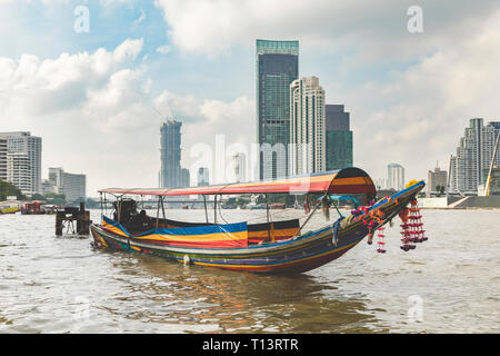 Thailand, Bangkok, typische Boot auf dem Chao Phraya Fluss mit Wolkenkratzer im Hintergrund Stockfoto