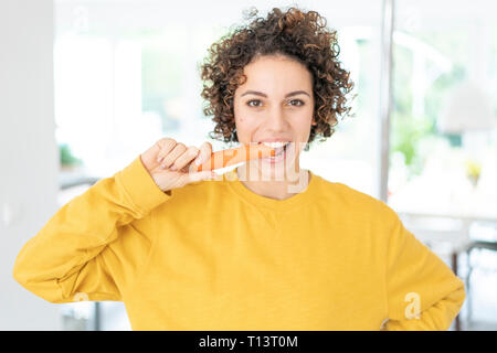 Portrait von Frau essen eine Karotte zu Hause Stockfoto