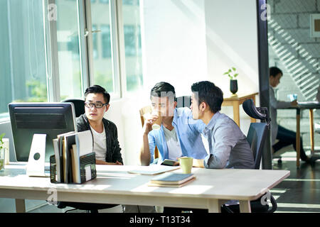 Drei jungen asiatischen Führungskräfte gemeinsam diskutieren business plan im Amt. Stockfoto