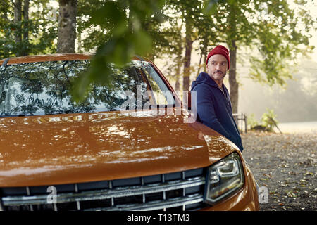 Reifer Mann im Auto im Wald schiefen Stockfoto