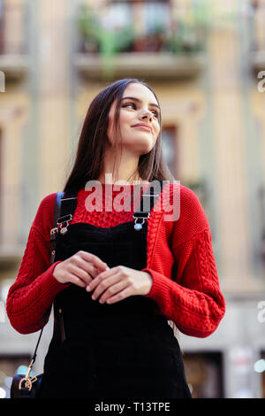 Portrait von modischen jungen Frau das Tragen der roten Strickpullover und schwarzen Trägerkleid Stockfoto