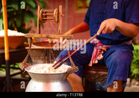 Man entspannen Seide aus Kokons in grossen Hot Pot Stockfoto