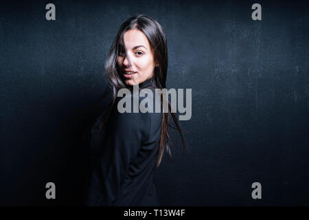 Porträt der jungen Frau mit schwarzen Blazer vor schwarzem Hintergrund Stockfoto