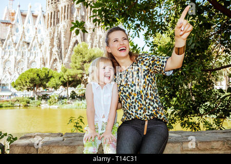 Barcelona - August, 06, 2015: Happy Elegant Mutter und Tochter an etwas gegen La Sagrada Familia in Barcelona, Spanien zeigt. Stockfoto