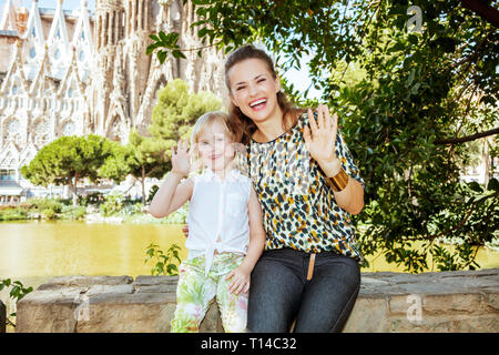 Barcelona - August, 06, 2015: Happy trendy Mutter und Kind Touristen nicht weit von La Sagrada Familia in Barcelona, Spanien handwaving. Stockfoto