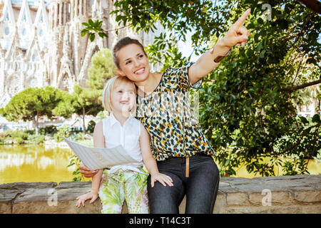 Barcelona - August, 06, 2015: Happy Elegant Mutter und Kind Touristen mit Karte bei etwas gegen La Sagrada Familia in Barcelona, Spanien zeigt. Stockfoto