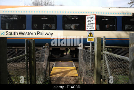 Ein South Western Railway Bahn macht es weise hinter einer Fußgängerzone Bahnübergang in der Nähe von Basingstoke, Hampshire. Stockfoto