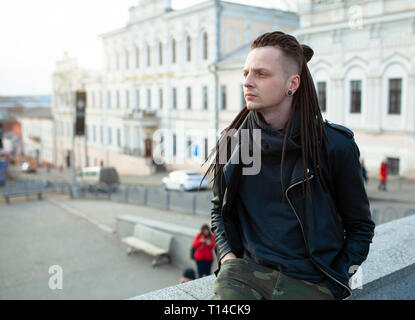 Rocker Rock Star jungen kaukasischen Mann mit Dreadlocks gehen auf die Straße der Stadt Herbst Tag. In das Leder Jacke angezogen Stockfoto