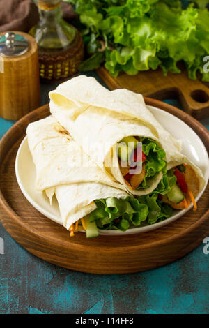 Gesundes Mittagessen Snack. Tortilla Wraps mit gegrilltem Huhn und frischem Gemüse auf der blauen Tabelle. Chicken Tortilla, Mexikanischen Straße fast food. Stockfoto