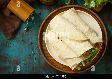 Gesundes Mittagessen Snack. Tortilla Wraps mit gegrilltem Huhn und frischem Gemüse auf der blauen Tabelle. Chicken Tortilla, Mexikanischen Straße fast food. Kopieren Sie Raum, Stockfoto