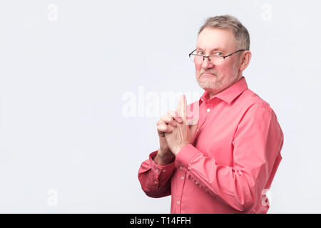 Älterer Mann im roten Shirt, das Gewehr Geste. Stockfoto