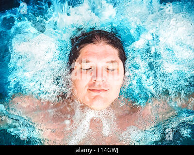 Glückliche Menschen entspannen im Whirlpool und schließen die Augen. Kaukasischen jungen ruht in einem Pool liegt im Wasser. Blick von oben. Schwimmen Kerl in einem Pool mit Stockfoto