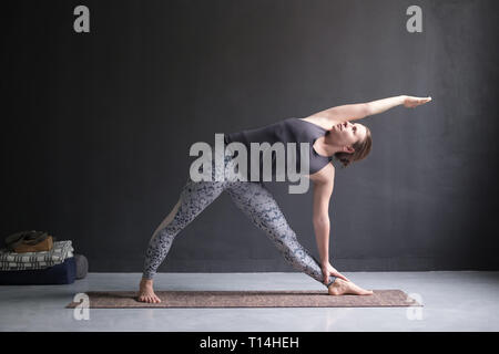 Frau Üben Yoga, Utthita Trikonasana darstellen Stockfoto