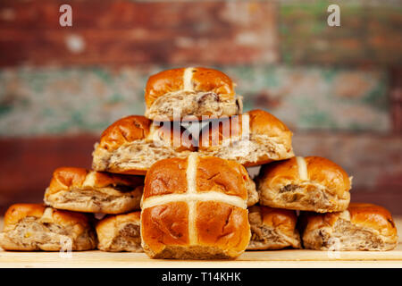 Stapel von frischen goldenen Hot Cross Buns gegen einen farbigen Hintergrund Stockfoto