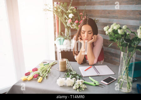 Weibliche Florist bei der Arbeit: hübsche junge dunkelhaarige Frau, die Mode moderne Blumenstrauß aus verschiedenen Blumen. Frauen arbeiten mit Blumen in der Werkstatt Stockfoto