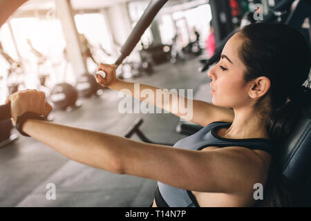 Ein Bild der schönen Mädchen, die die Push-ups in der Maschine. Sie ist konzentriert und ernst. Close Up. Schneiden. Stockfoto