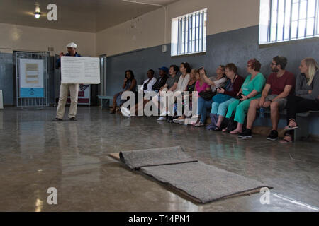 Touristen hören, ein ehemaliger Häftling, der jetzt einen Reiseführer, in eine gemeinsame Zelle auf Robben Island, wo Nelson Mandela während der Apartheid inhaftiert war, Sechskantschrauben Stockfoto