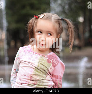 Hübsches kleines Mädchen auf dem Hintergrund der Stadt Brunnen Stockfoto