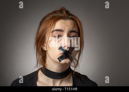 Erschrocken schrie Mädchen mit Klebeband auf den Mund an Kamera suchen Stockfoto