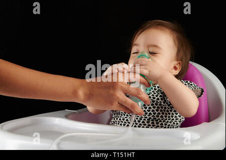 Kleines Mädchen Atmung mit Inhalator auf schwarzem Hintergrund Stockfoto