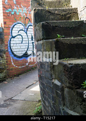 Stein Schritte vor einer Schleuse, Trent und Mersey Canal, Stoke-on-Trent, Staffordshire, Großbritannien. Graffiti im Hintergrund Stockfoto