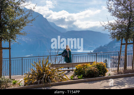 Ein Bild von einem Mädchen, das auf einem Hügel im Hintergrund den Luganer See und die Alpen im Tessin Kanton der Schweiz Stockfoto