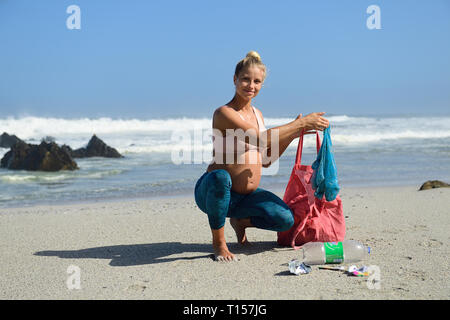 Schwangere Frau Reinigung der Strand von Kunststoffabfällen Stockfoto