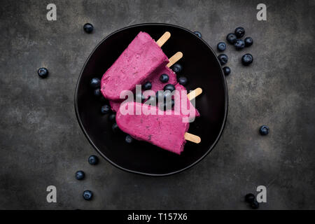 Schüssel mit heidelbeere Eis am Stiel und Blaubeeren Stockfoto