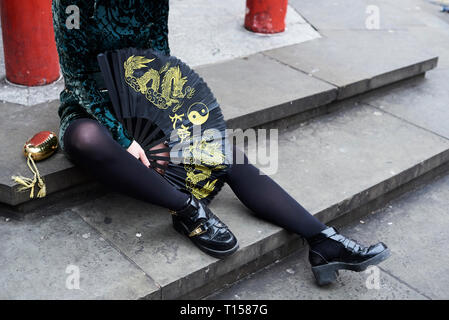 London, junge Frau mit chinesischen Ventilator in Chinatown, sitzen auf den Schritten Stockfoto