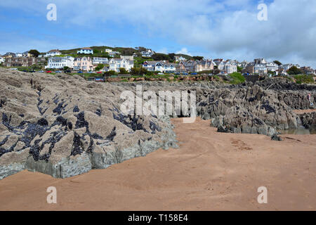Zerklüftete Felsen auf Woolacombe Strand mit Blick auf Hotels, Apartments am Meer und andere Gebäude, von Woolacombe Bay, Devon, Großbritannien Stockfoto