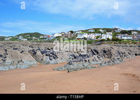 Zerklüftete Felsen auf Woolacombe Strand mit Blick auf Hotels, Apartments am Meer und andere Gebäude, von Woolacombe Bay, Devon, Großbritannien Stockfoto