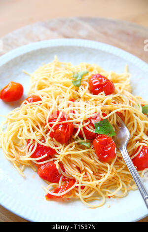 Cherry Tomaten in Olivenöl und Knoblauch über Pasta gekocht Stockfoto