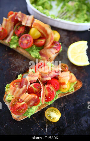 Speck und Kirschtomaten auf Toast mit Guacamole Stockfoto