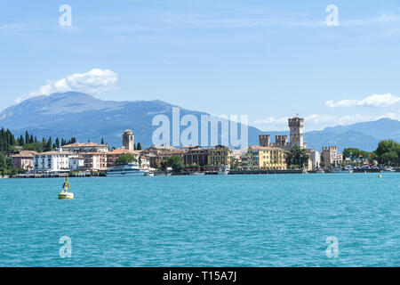 Blick auf Sirmione vom Gardasee mit Bergen im Hintergrund. Sirmione ist mittelalterliche Stadt Sirmione, Italien - August 2017. Stockfoto