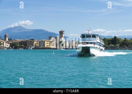 Sirmione, Italien - 07 August 2017: Touristische Schiff am Gardasee. Panorama von Sirmione, Caligero Schloss und die Berge im Hintergrund. Stockfoto