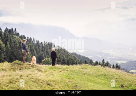 Österreich, Tirol, Kaisergebirge, Mutter und erwachsener Sohn mit Hund auf eine Wanderung in den Bergen Stockfoto