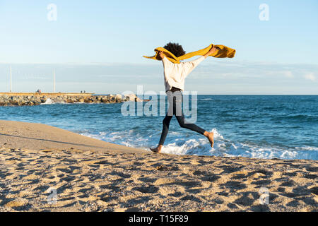 Frau, die auf dem Strand, tragen gelbe Schal Stockfoto