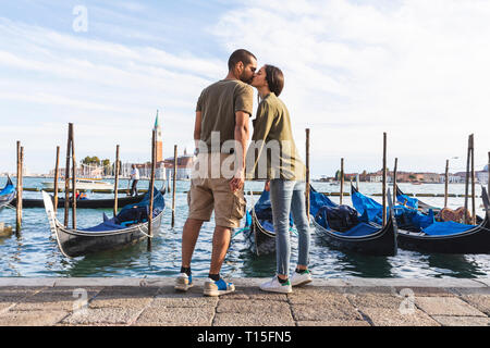 Italien, Venedig, liebevolle junge Paar Küssen mit Gondel Boote im Hintergrund Stockfoto