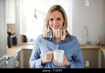 Porträt der lächelnde Frau eine Tasse Kaffee zu Hause Holding Stockfoto