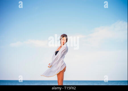 Schöne junge Frau in ein Handtuch gewickelt am Strand Stockfoto
